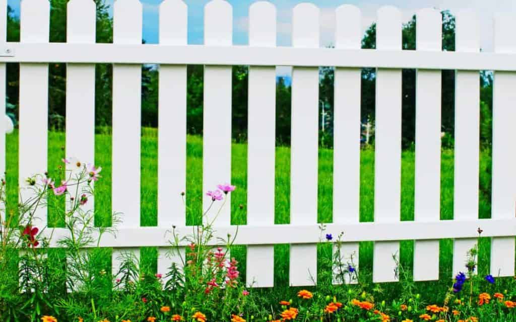 A section of white picket fence lined with Texas wild flowers in the spring
