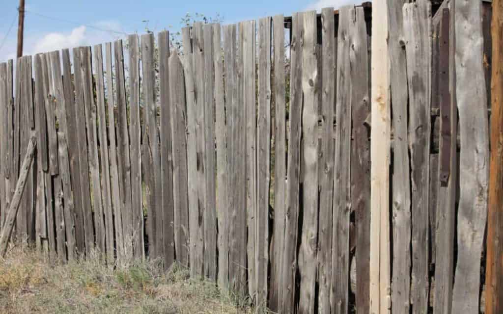 An ugly aging wood fence weathered with age needs to be replaced.